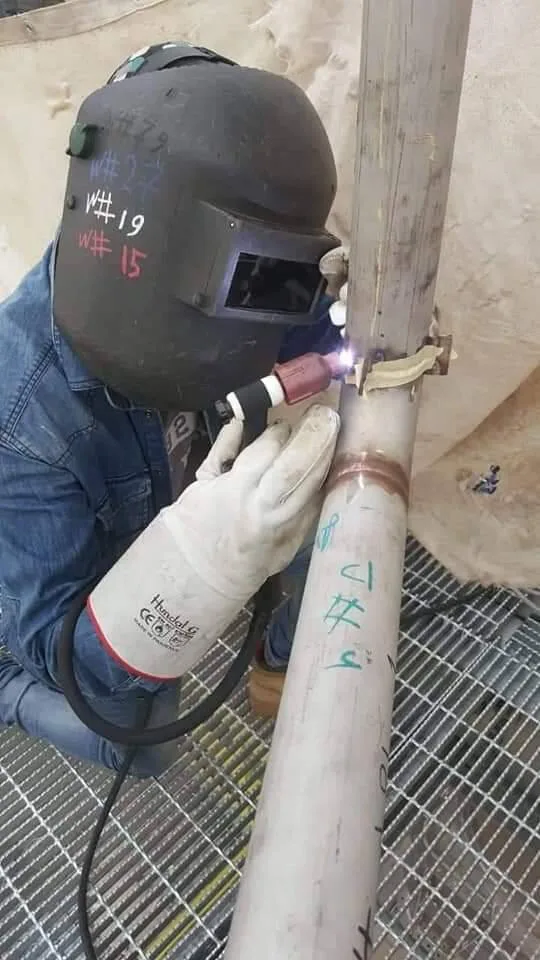 Industrial welder performing TIG welding on stainless steel pipe